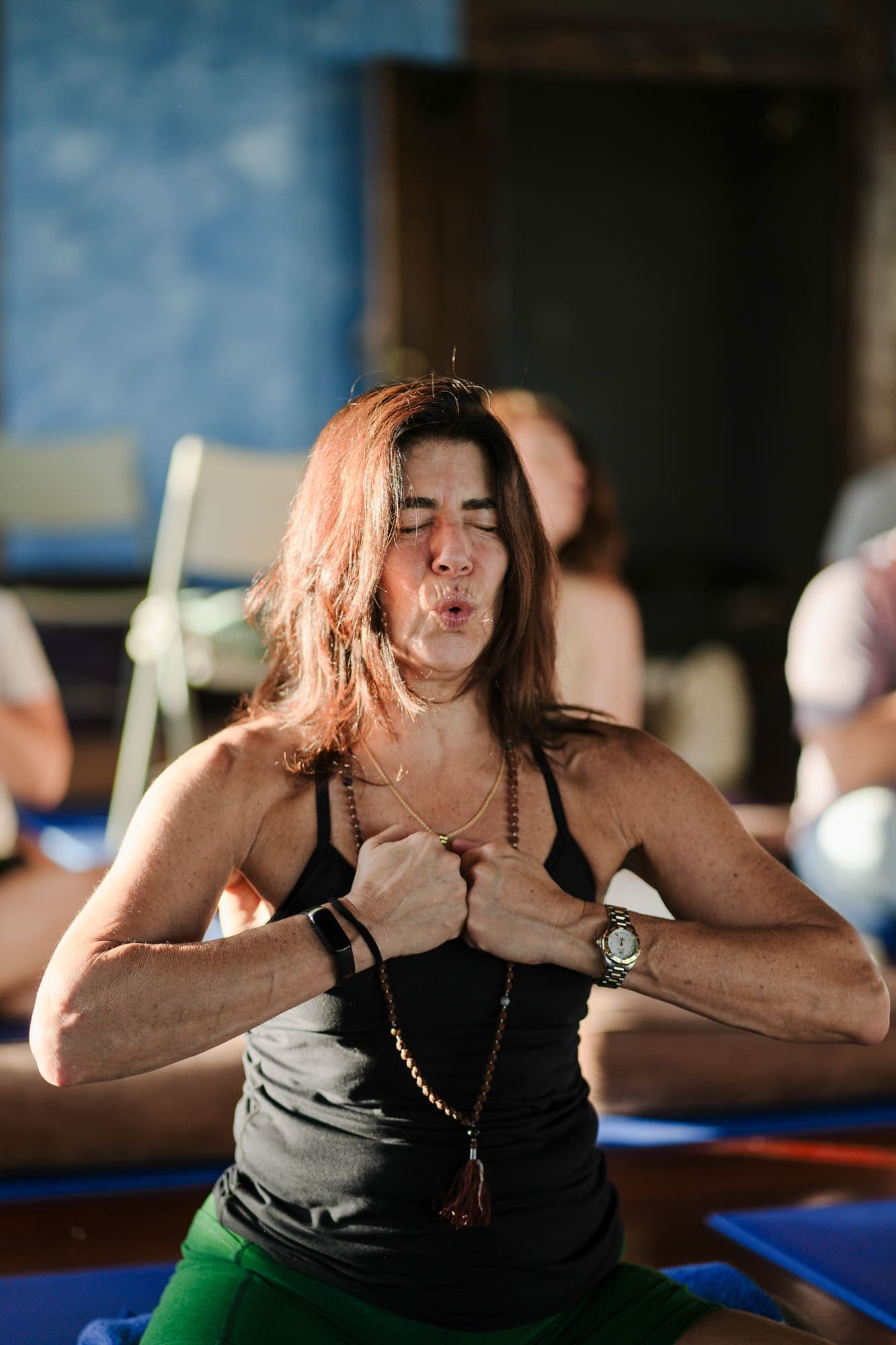 Woman in a breathwork practice, fists at her chest, eyes closed in a moment of release