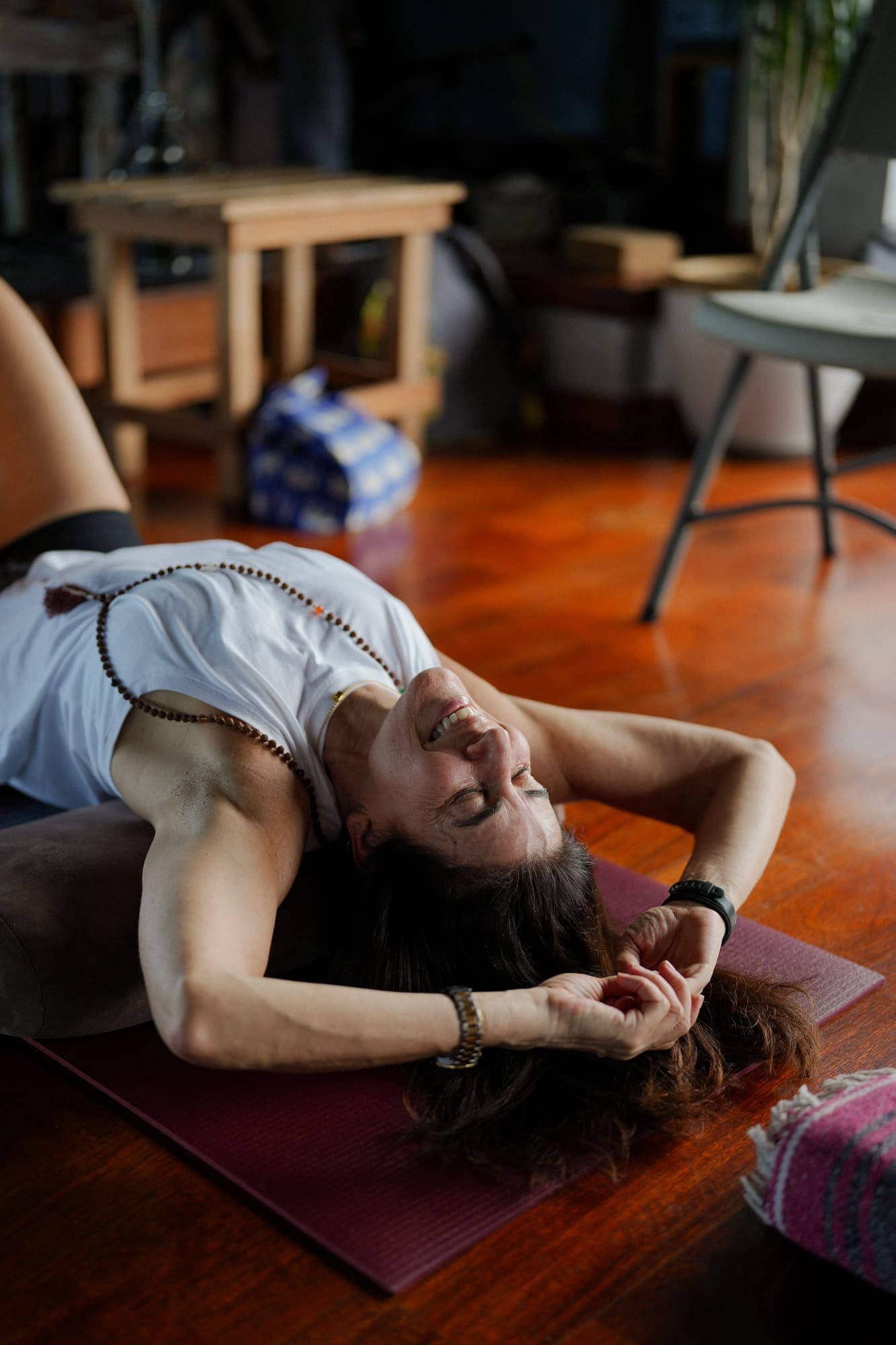 Woman smiling in a relaxed backbend stretch on a yoga mat