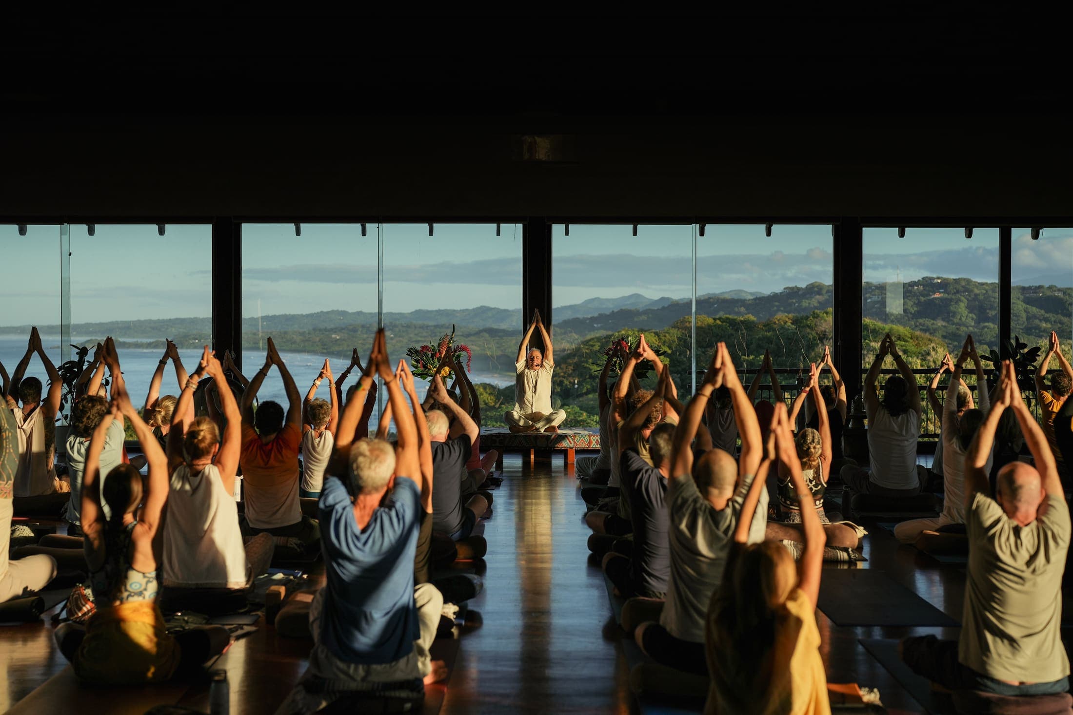 Group meditation retreat at sunrise overlooking the coastline