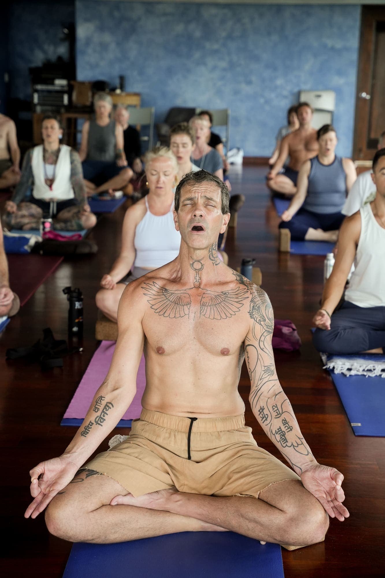 A man deep in group breathwork, eyes closed, in the raw and vulnerable work of release