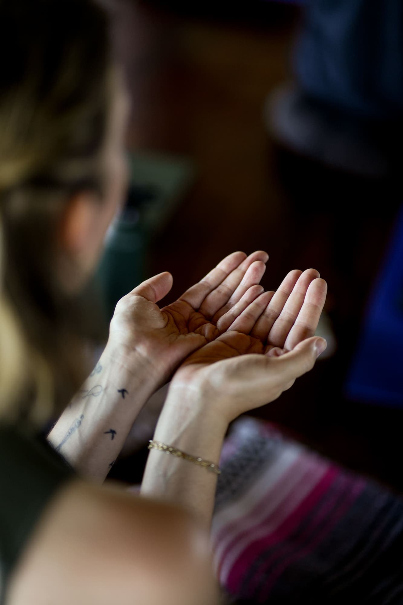 Two people's open, cupped hands touching in a gesture of giving and receiving