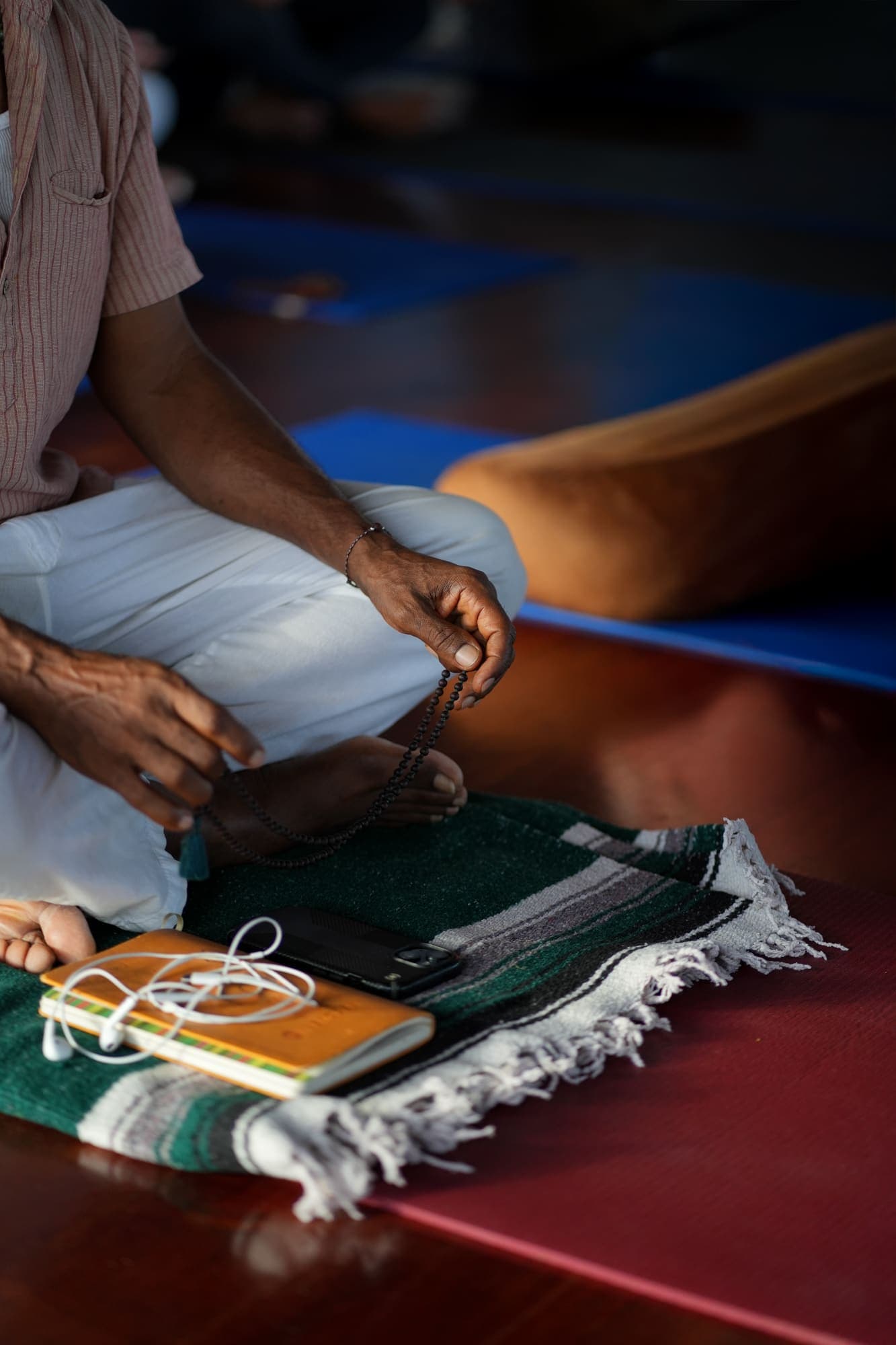 Hands holding mala beads over a journal and phone, a quiet moment of personal practice